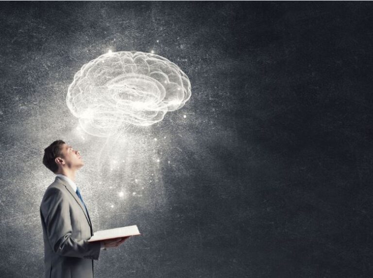 Business man holding a book and looking up at an imagination of a brain representative of peeking into someone's mind
